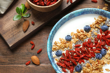 Smoothie bowl with goji berries on wooden table, closeup
