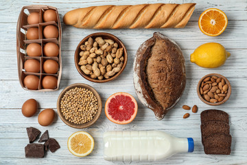Flat lay composition of different products on white wooden table. Food allergy concept