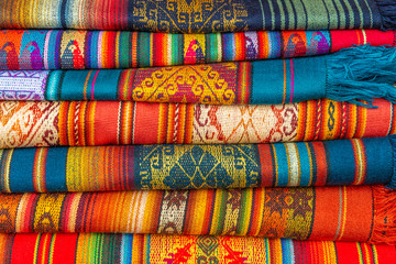A pile of colorful Andes textiles on the sunday art and craft market of Otavalo in Ecuador, north...