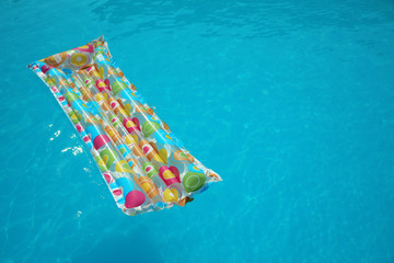 Colorful inflatable mattress floating in swimming pool on sunny day. Space for text