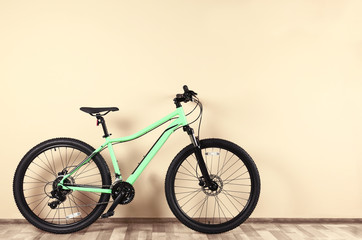 Fototapeta premium Modern bicycle near beige wall indoors. Healthy lifestyle