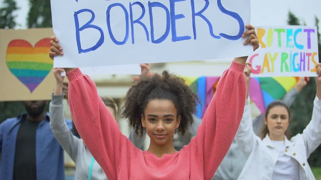 Woman holding Love without borders poster together with LGBT activists, pride