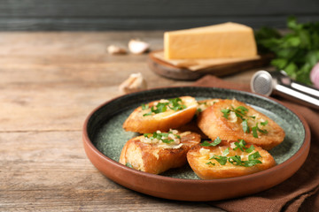 Slices of toasted bread with garlic, cheese and herbs on wooden table