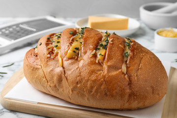 Delicious homemade garlic bread with herbs and cheese on table, closeup
