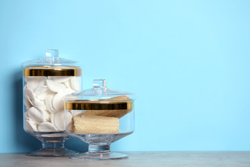 Composition of glass jar with cotton pads on table near blue wall. Space for text