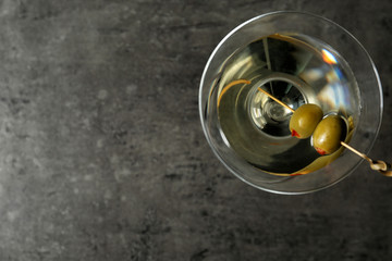 Glass of Classic Dry Martini with olives on grey table, top view. Space for text
