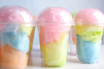 Many plastic cups with tasty cotton candies on white wooden table