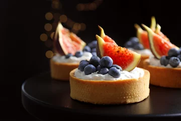 Foto op Plexiglas Tarts with blueberries and figs on black table against dark background, closeup. Delicious pastries © New Africa