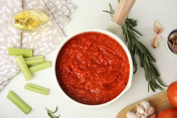 Flat lay composition with delicious tomato sauce in pan on white table