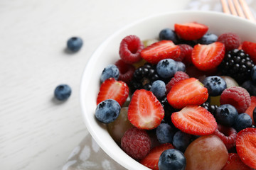 Fresh tasty fruit salad on white wooden table, closeup