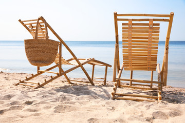 Wooden deck chairs on sandy beach near sea