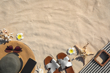 Flat lay composition with different beach accessories on sand. Space for text