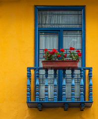 Balcony with blue window frame and yellow wall in the historic city center of Cuenca, Ecuador.