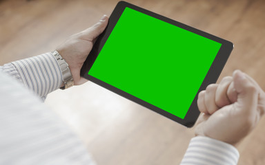 Male hands holding tablet with green screen - success concept man celebrates wining