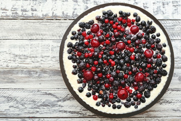Berry pie with cherry, currant, blackberry, blueberry on white wooden table . Cheesecake, top view with copy space.