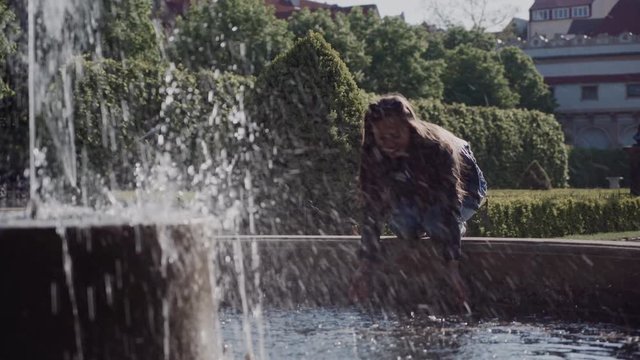 happy girl splashes in beautiful fountain in park. General plan