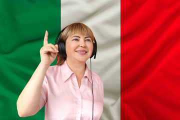 woman in headphones against the background of the national flag of Italy on delicate shiny silk,...