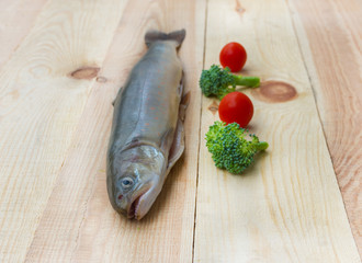 Raw rainbow trout river fish on a wooden background with vegetables