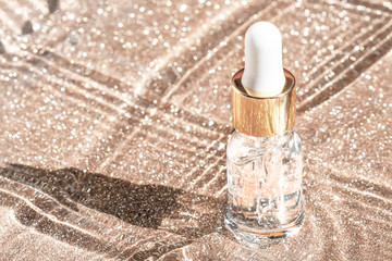 Anti aging serum with collagen and peptides in glass bottle with dropper on golden background....