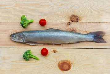 Raw rainbow trout river fish on a wooden background with vegetables