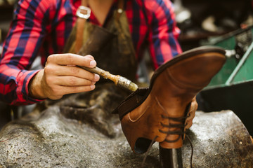 Hands of a shoemaker gluing a shoe in a workshop