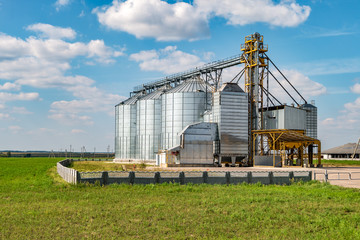 Fototapeta na wymiar silver silos on agro manufacturing plant for processing drying cleaning and storage of agricultural products, flour, cereals and grain. Granary elevator