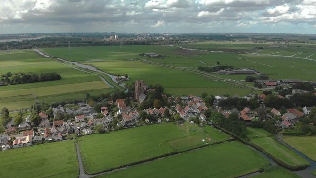 Dramatic aerial panoramic view of the agrarian green pasture fields with its irrigation infrastructure of ditches and trenches surrounding the small traditional village of Ransdorp near Amsterdam
