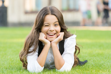 Winking to you. School break for rest. Adorable pupil. Girl kid laying lawn. Girl school uniform...