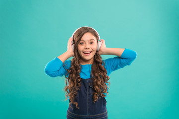 Feeling the beauty of the song. Cute small child listening to song on blue background. Adorable little girl enjoying song playing in headphones. Composing a song