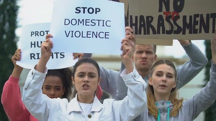 Crowd chanting slogans on domestic violence rally waving banners for human right