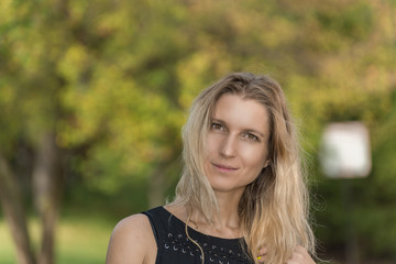 Fototapeta premium Attractive blonde young woman in a park with blurred background
