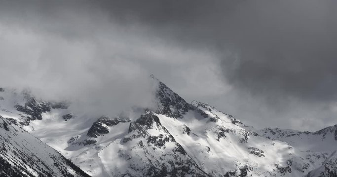 4K Time Lapse of Dramatic Snow Covered Alpine Peak Surrounded by Storm Clouds