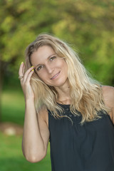 Naklejka premium Attractive blonde young woman in a park with blurred background