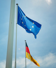 German and European Union flags waving with clear blue sky in the background
