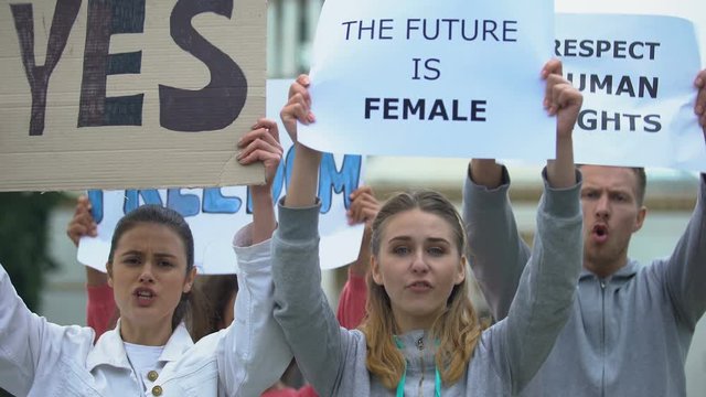 Feminist protesters chanting waving banners, protection of women rights equality
