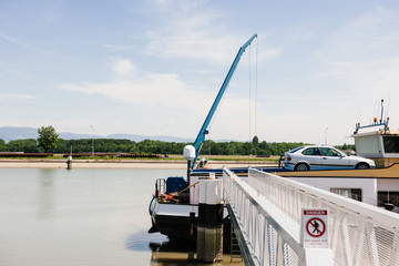Strasbourg, France - Jun 2, 2013: Rear part of large cargo barge tanker boat transporting car in upper deck transport on Rhine River with Germany Black Forest Mountains in the background