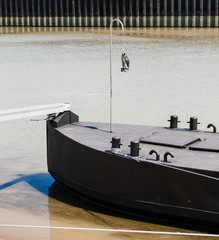 Square image of rear part of old tanker cargo barge ship on Rhine River with owl lucky doll on the front