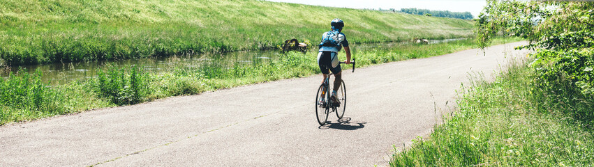 Rear view of male cyclist riding a sport bike near Rhine River in France