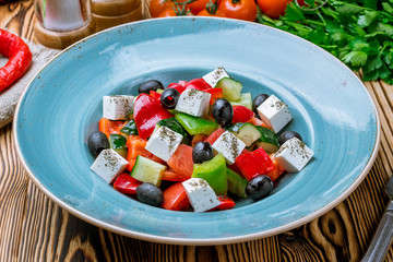 Greek salad with feta and vegetables on wooden table