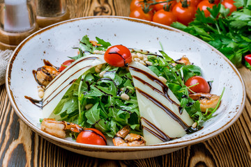 Arugula with shrimps and tomatoes on wooden table