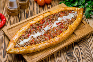 Turkish pide with minced meat and cheese on wooden table. Turkish cuisine.