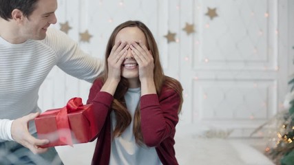 Cheerful woman closing eyes with hands in luxury house. Smiling couple hugging