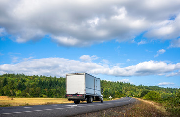 Compact big rig semi truck with long box trailer running on the road for delivery commercial goods