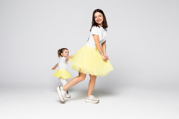 Young mother playing with little daughter in dresses isolated on white background