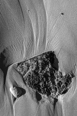 ROCK TEXTURE COVERED FROM BEACH SAND. BLACK AND WHITE PHOTOGRAPHY