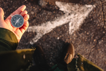 Hipster traveler holding compass in the hand making choice in what direction to go