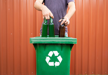 Man putting beer glass bottles into recycle bin for glass 