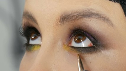 Professional stylist make-up artist makes eye makeup model. Face model with evening make-up close up view