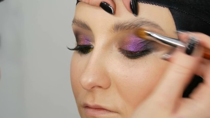 Fashionable multi-colored eye shadow chameleon with yellow purple gray silver color on the eyelid of a beautiful girl model with brown eyes. Professional cosmetic makeup. Eye close up view