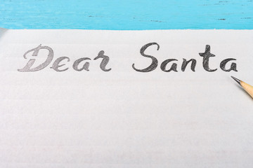 letter paper with hand written Dear Santa and a pencil on table